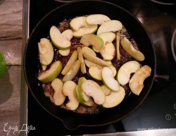 Яблоки нарезаем пластинками и выкладываем в карамель. Аккуратно перемешиваем, чтобы карамель покрыла яблоки равномерно. Убираем сковородку в разогретую духовку.