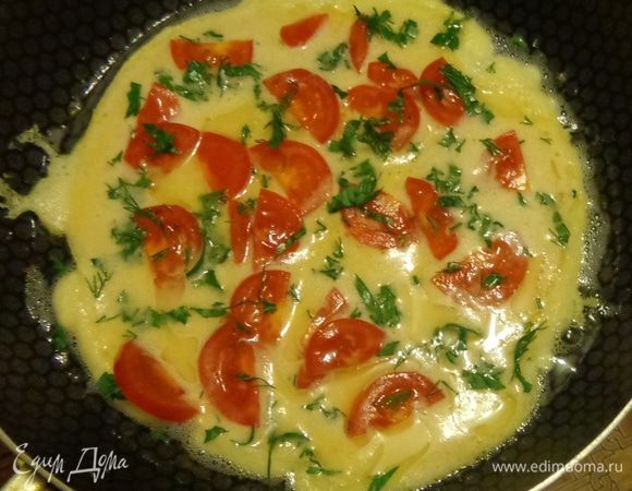 Аккуратно смешать обе массы и жарить на раскаленной сковороде пока не схватятся края. После этого уложить по всей поверхности помидоры и зелень.