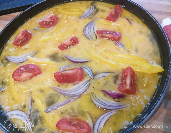Разогреть на сковороде сливочное и оливковое масло, вылить яичную смесь, разложить дольки помидор, лук и перец, накрыть крышкой и тушить на умеренном огне минуты 3.