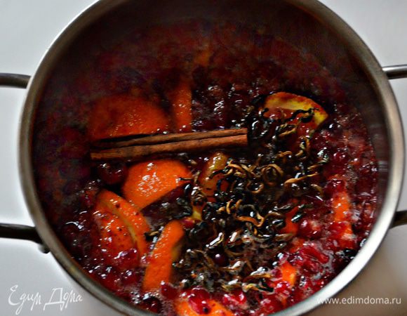 Сразу поставьте на огонь кастрюлю с водой и дайте ей закипеть. В это время промойте клюкву и слегка разомните толкушкой. Апельсин промойте и обдайте кипятком. Добавьте к клюкве половину апельсина, нарезанного небольшими дольками. Затем насыпьте столовую ложку заварки зеленого чая, порезанный небольшой кусочек (0,5-0,7 мм) имбиря и добавьте палочку корицы. Залейте все литром крутого кипятка. Поставьте кастрюльку на средний огонь и проварите 1 минуту.
