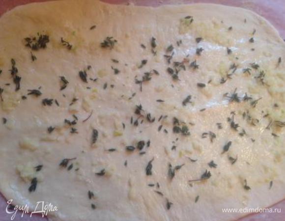 Тесто раскатать в прямоугольный пласт, смазать растительным маслом, равномерно распределить пропущенный через пресс чеснок и притрусить зеленью (у меня тимьян).
