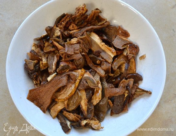 Замоченные грибы слейте и как следует отожмите. Добавьте их в сотейник к овощам. Помешивая, дайте грибам хорошо обжариться, до появления интенсивного запаха.