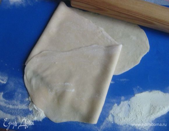 Взять первый колобок. Раскатать его тонко на поверхности, припудренной мукой, положить длинной стороной к себе. Вырезать прямоугольник с короткой стороной 11-11.5 сантиметров. Другая сторона — произвольной длины, но достаточно длинная, чтобы свернуть затем рулет. 