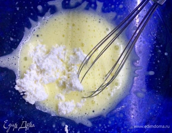 Продолжая процесс взбивания, добавляем по ложке еще не остывшую творожную массу и тщательно взбиваем. 