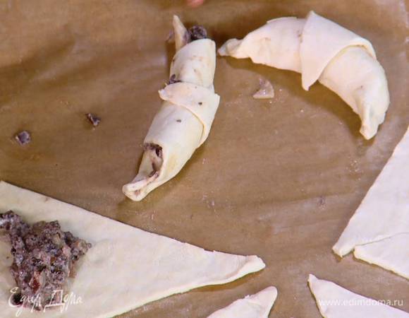 На широкое основание каждого треугольника выложить по 1–2 ч. ложки начинки и сделать круассаны, скручивая от большей стороны треугольника к меньшей.