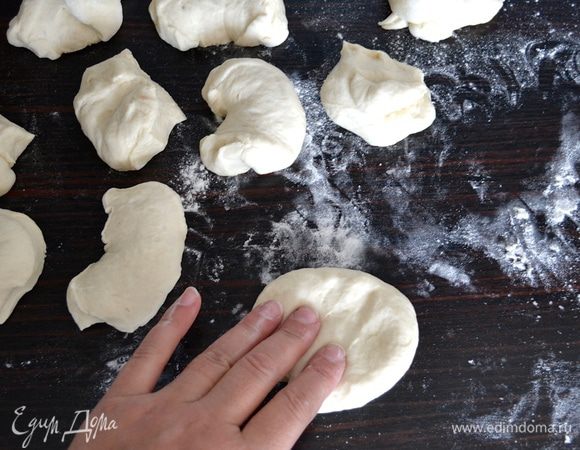 Готовое тесто аккуратно выложите на подпыленную мукой рабочую поверхность и скатайте в шар. Разделите на 2 равные части, лучше всего использовать весы — каждая половина теста будет по 450 г. Каждую часть теста поделите на 9 маленьких равных кусочков по 50 г. Возьмите один кусочек теста, слегка придавите его рукой, чтобы вышел лишний воздух. 