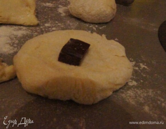 Разделить тесто на кусочки. Расплющить кусочек, внутрь положить кусочек шоколада. Защипнуть, сформировать булочку.
