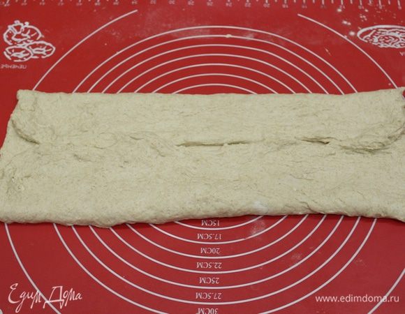 Затем присыпаем рабочую поверхность немного мукой. Выкладываем тесто. Раскатываем в квадрат, примерно 40х40 см. Складываем тесто к середине. 