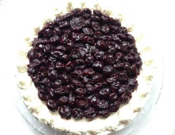 Сверху выложить второй корж, намазать верх и бока оставшимся кремом (при желании немного оставить для украшения) и выложить оставшуюся вишню (я снова полила столовой ложкой коньяка). Поставить торт в холодильник на ночь для пропитки.