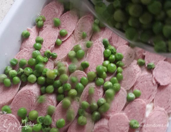 Сосиски порезать наискось или кружочками, уложить на пюре. Сверху равномерно высыпать горошек.