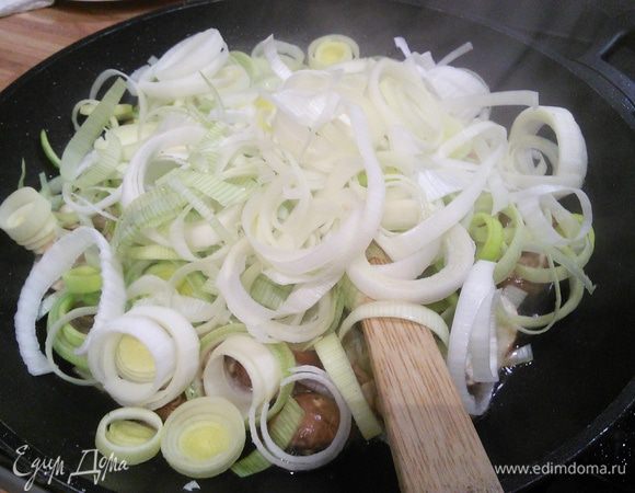 Добавляем порезанную кружочками светлую часть крупного лука-порея, обжариваем с грибами несколько минут до готовности лука. Солим, перчим. 
