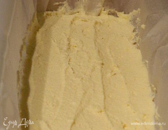 Форму смазать маслом и выстелить пекарской бумагой. На дно формы выложить творожную массу. Разровнять.