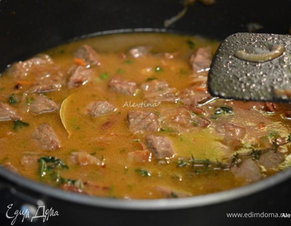 Прибавить огонь, налить вина в блюдо, довести до кипения, помешивая.  Убавить до среднего и готовить 3-5 мин. Добавить бульон, томатную пасту и перемешать. Довести до кипения, убавить огонь. Закрыть крышкой и тушить 1,5 часа.