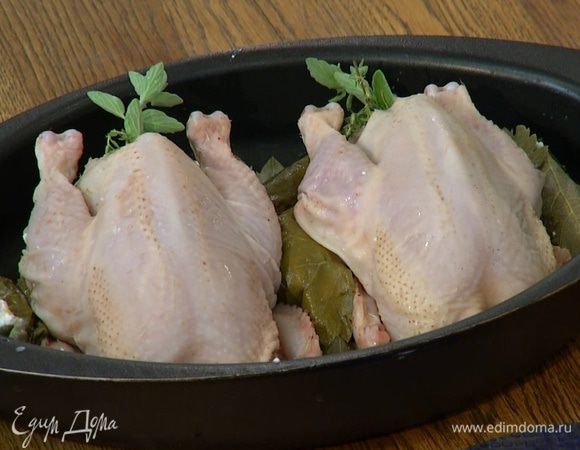 Дно небольшой формы для выпечки выстелить оставшимися виноградными листьями, выложить фаршированных цыплят грудками вверх, рядом поместить оставшиеся творожные рулетики.