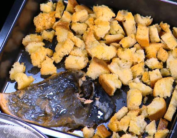 Готовые крутоны поместить в небольшой глубокий противень, сбрызнуть оливковым маслом, выложить в противень кожу от семги и отправить все разогретую духовку на 3 минуты.