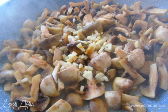 Отправьте грибы на сковороду, где жарилась курица, чуть обжарьте и добавьте измельченный чеснок.