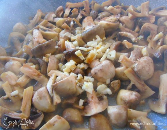 Отправьте грибы на сковороду, где жарилась курица, чуть обжарьте и добавьте измельченный чеснок.