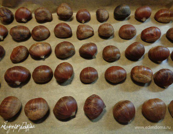 Положить каштаны на противень, застеленный пекарской бумагой, надрезами вверх. И поставить в разогретую до 200°С духовку на 20-25 минут.


