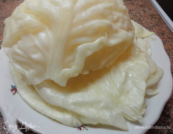 Кочан капусты надрежьте у кочерыжки, опустите в кипящую воду — он будет хорошо разбираться на листья. Листья надо подержать в горячей, почти или совсем кипящей воде 5 минут. Вынуть, остудить, срезать утолщения.