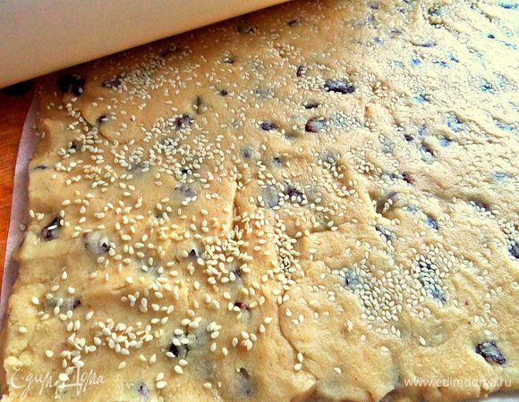 Раскатать прямо на бумаге тесто толщиной в 0,5 см. Сверху снова посыпать семечки. Слегка прокатать верх скалкой.