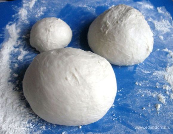 Духовку разогреть до 200°C.
Вынуть тесто из кастрюли, поместить на рабочую поверхность, обсыпанную мукой. Разделить на 3 шара: 2 — большие, 1 — небольшой для окантовки пирога. Оставить их на 15 минут.
