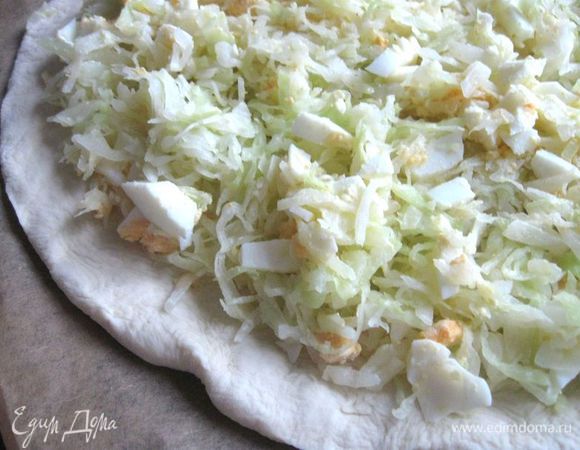 Раскатать тесто для нижней части пирога круглой формы, намотать его на скалку и переложить на противень, застеленный пекарской бумагой. Положить начинку на нижнюю часть, отступив от края 3 см.   
