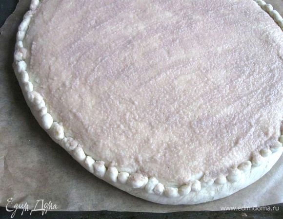 Раскатать тесто для верхней части чуть меньшего диаметра, чем нижняя часть. Накрыть им начинку, приподнять нижний слой с краев, защипнуть края, пройтись слегка скалкой по верху пирога, чтобы выровнять поверхность. Украсить пирог окантовкой по вашему усмотрению. Смазать поверхность сплошным, но не толстым слоем гречневой муки, разбавленной водой до состояния сметаны. 
