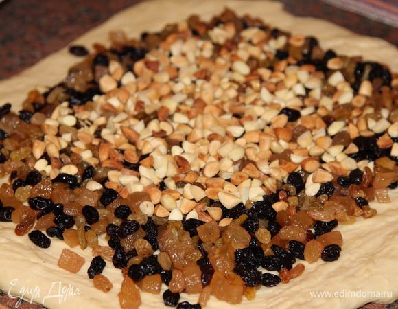 Теперь раскатываем тесто в квадрат и высыпаем на него подготовленные изюм с цукатами и орехи.