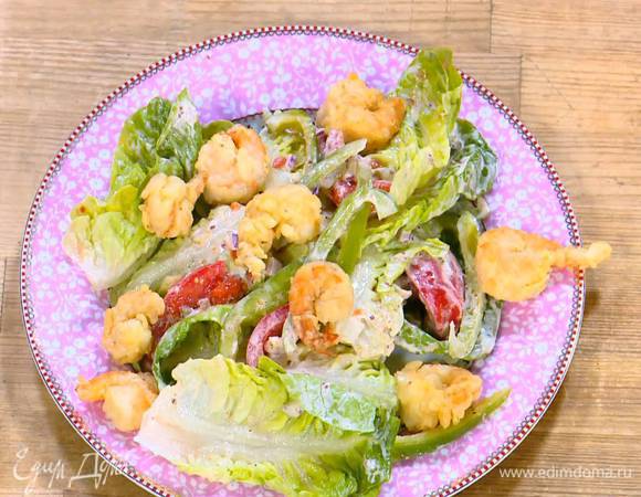 Салат с овощами переложить на блюдо, сверху выложить обжаренные креветки и оставшуюся заправку.