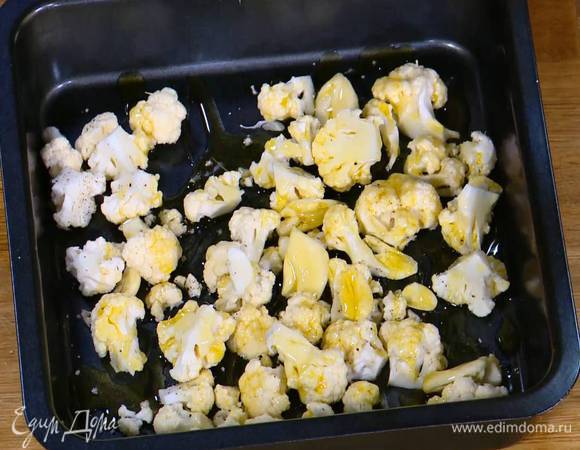 Выложить цветную капусту в небольшой противень, посолить, поперчить, добавить чеснок, сбрызнуть оливковым маслом, слегка встряхнуть, чтобы капуста промаслилась, и запекать под грилем 5 минут.