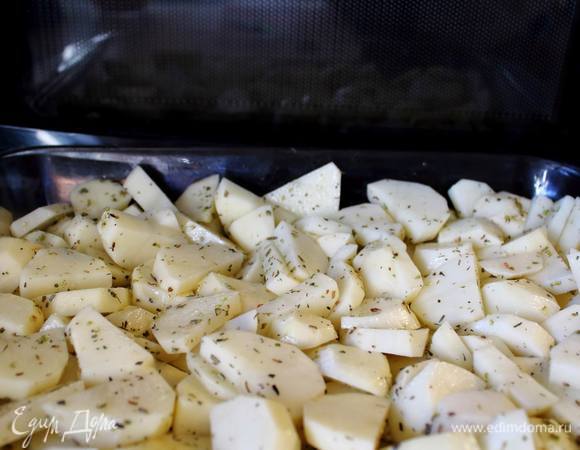 Картофель порезать полукольцами, толщиной около 1 см. Уложить в емкость для выпекания, посолить, поперчить, присыпать травками, полить оливковым маслом и хорошенько ее в этом всем "вывалять" :)