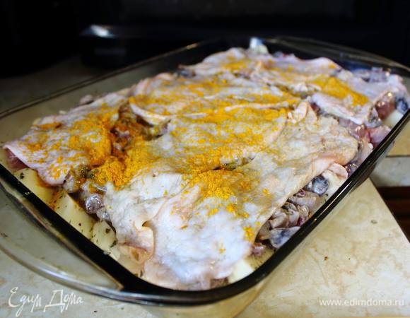 Уложить на картошку с бедрышками тушеные в сметане с луком шампиньоны и укрыть все оставшимися шкурками. Я посыпала куркумой — она придаст корочке красивый цвет. Можно и более классическое решение — посыпать тертым сыром.