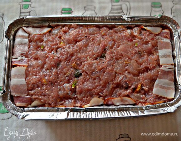 Форму застелите фольгой либо возьмите форму из фольги в два слоя (объемом 1 литр). Выложите в форму бекон так, чтобы концы свешивались за края формы. На бекон переложите фарш, уплотните его в форме и разровняйте. Сверху можно так же закрыть беконом, накройте фольгой.