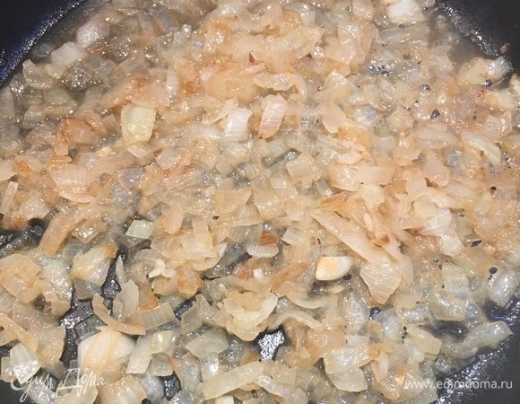 Оставшийся лук нарезаем не очень мелко, промазываем кисточкой сковородку с антипригарным покрытием одной ложкой оливкового масла и тушим в ней лук. Можно добавлять несколько ложек бульона от печени, чтобы лук не прожарился, а потушился.