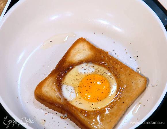 Разогреть в сковороде оливковое масло и обжаривать хлеб с одной стороны до появления золотистой корочки, затем перевернуть, разбить в вырезанные выемки по яйцу, посолить, поперчить и жарить на медленном огне до готовности яиц.