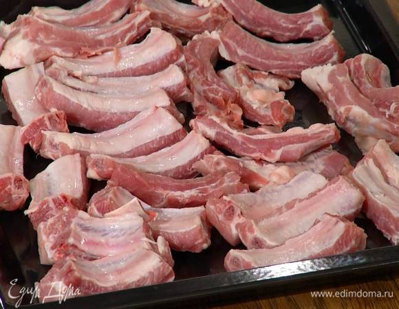 Свинину нарезать вдоль ребер и выложить на противень.
