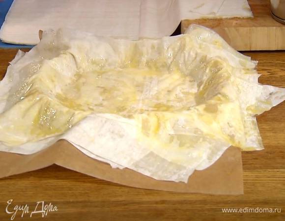 Листы фило смазать с одной стороны растопленным сливочным маслом и уложить в форму один на другой внахлест, так чтобы концы теста свешивались в разные стороны.