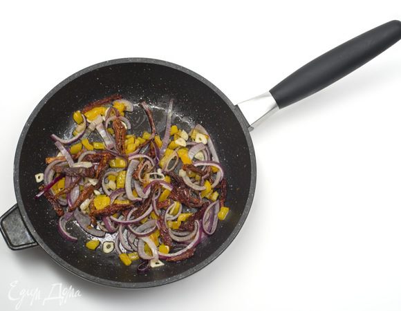 Перец нарезать кубиками, лук нарезать кольцами, чеснок мелко порубить. Вяленые помидоры нарезать вдоль. Спаржу промыть и отрезать грубую часть. Обжарить ингредиенты в следующем порядке: сначала перец, затем добавить помидоры, затем лук и затем чеснок. Обжаривать на среднем огне, постоянно перемешивая.

