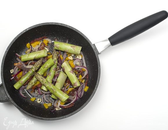 Когда лук станет золотистым, добавить спаржу и обжаривать все еще в течении 5 минут.


