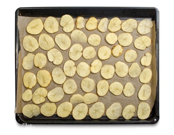 Картофель тщательно помыть, нарезать тонкими кружками и выложить на противень, застеленный бумагой для выпечки.



