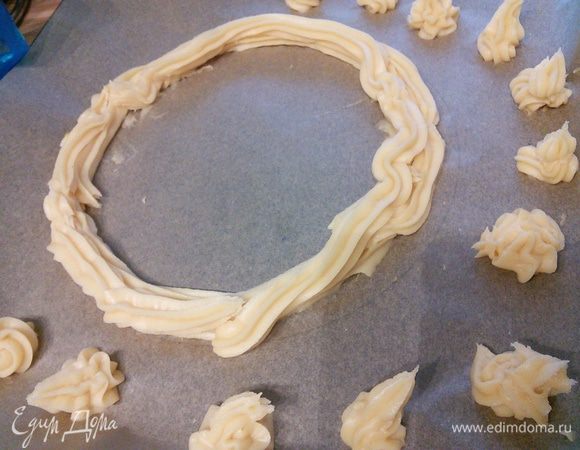 Пергамент перевернуть на обратную сторону. Отсадить круг диаметром 25 см, на него ещё один круг, а рядышком 12 мини-эклерчиков. 