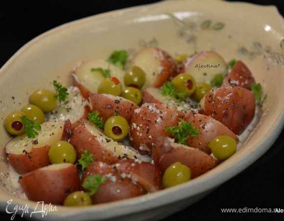 Картофель горячий порезать на половинки. Добавить заправку, оливки без косточек и перемешать. Украсить по желанию свежей зеленью. Подавать теплым к столу. 
