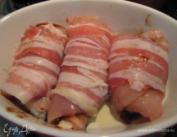 Каждый рулетик обернуть полоской бекона.
Форму для выпечки смазать оливковым маслом, положить рулетики, веточку розмарина. Если есть сливы, положить сливы, присыпать сахаром.