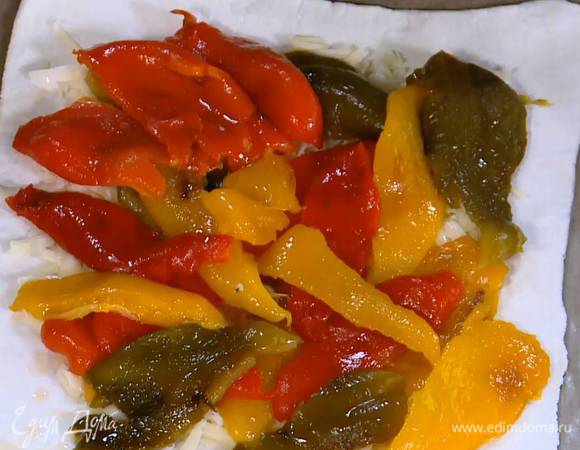 Тесто раскатать на бумаге для выпечки. Отступая от краев на пару сантиметров, выложить сладковатый сыр, на него поместить полоски сладкого перца и карамелизированный лук, посыпать все натертым твердым сыром.