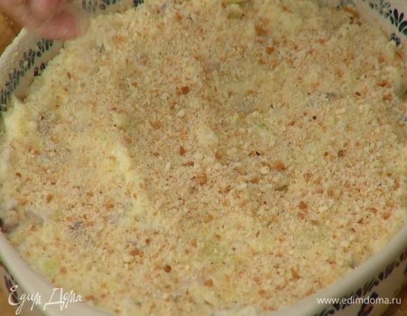 Керамическую жаропрочную форму смазать оставшимся сливочным маслом, присыпать дно и бока частью хлебной крошки, выложить селедочную массу, разровнять и посыпать сверху оставшимися сухарями.