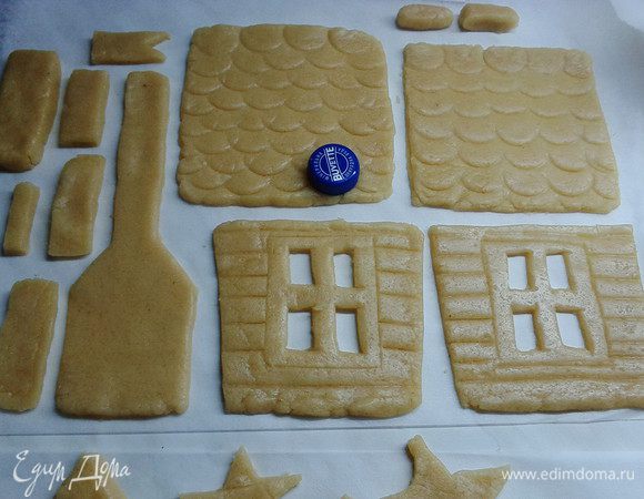 По желанию, для реализма, можно сделать черепицу на крыше, используя пробку от пластиковой бутылки. Ножом или линейкой на тесте нанести полосы, имитирующие бревна. Вырезанные части дома на пергаменте (на котором раскатывали тесто) переносим на доску и отправляем в холодильник на 30 минут. Для экономии места в холодильнике  листы пергамента с заготовками можно сложить друг на друга. Целесообразнее в холодильник отправить не колобок теста, а вырезанные из него части дома, так во время выпекания будет более ровная поверхность у готовых изделий.