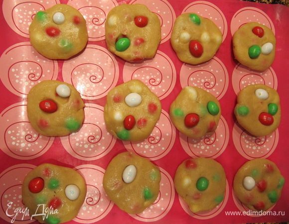 Скатать печенье, сверху вдавить в каждую печеньку 1-2 конфеты M&M's из отложенного 1/2 стакана. Отправить печенье в морозилку на 30 минут.