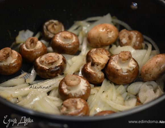 Обжарить на этой же сковороде тонко порезанную луковицу, очищенные грибы шампиньоны, крупные порезать на части. Обжаривать 7 минут помешивая. Добавить мелко порубленный чеснок, обжаривать 1 минуту.