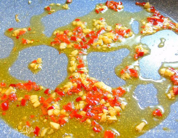 На растительном масле обжарить 15-20 секунд перец чили и чеснок.