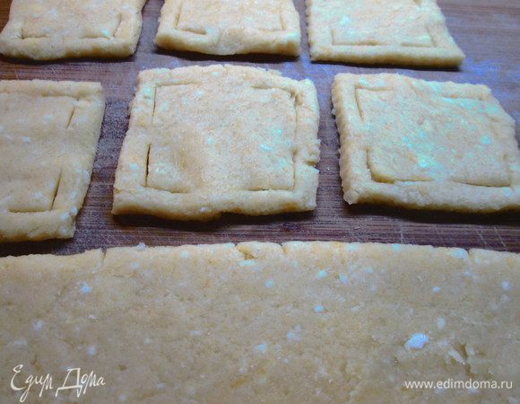 Отвариваем 2 яйца и натираем на мелкой терке. Смешиваем муку, вареные яйца, масло, сахар, желток и цедру.
Тесто раскатываем в пласт, толщиной 0,3 см. Разрезаем на квадраты, величиной приблизительно 7,5х7,5. Делаем в них прорези по углам, отступив от края 0,5 см.